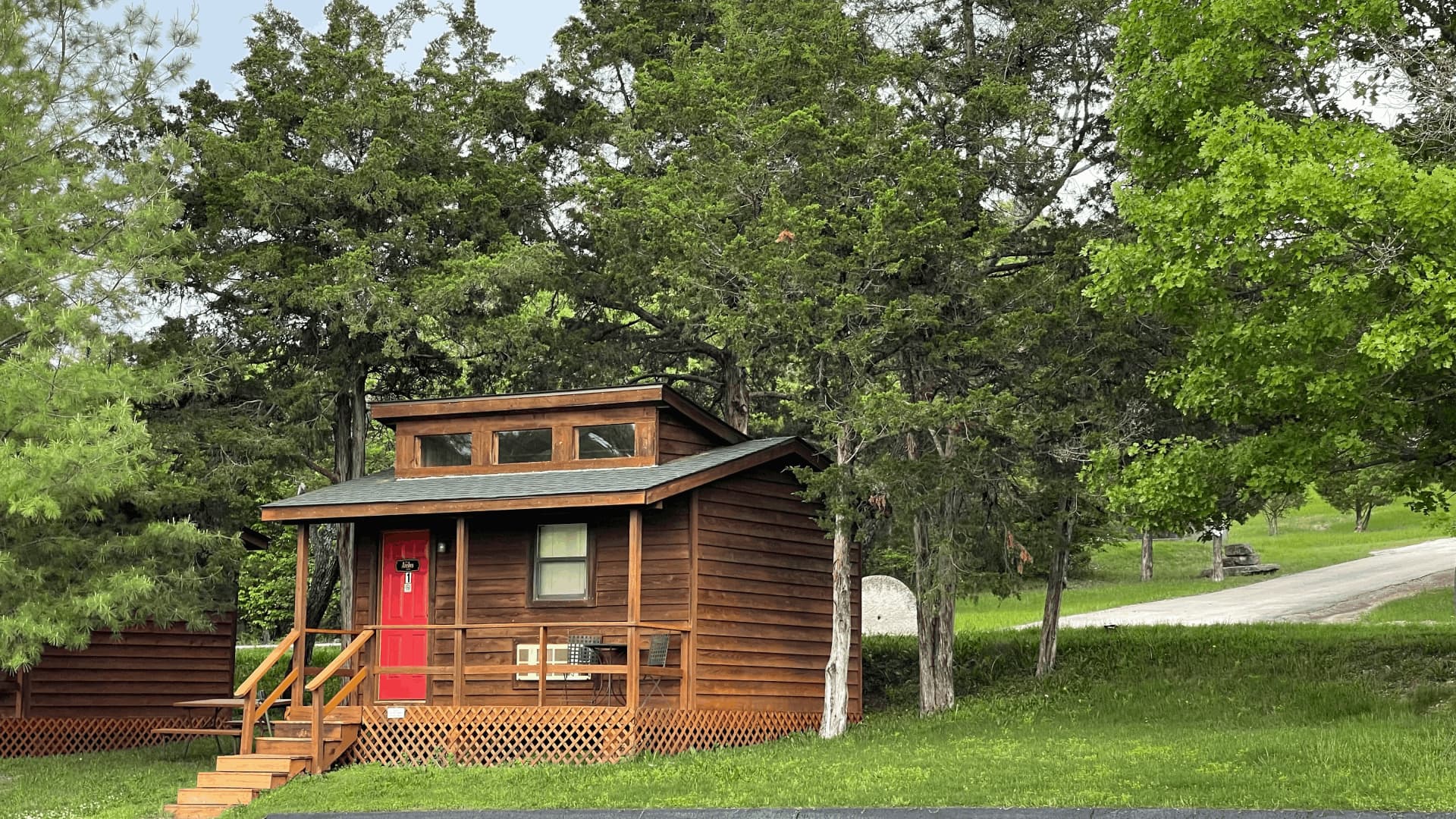 A small wooden cabin with a red door is situated in a wooded area